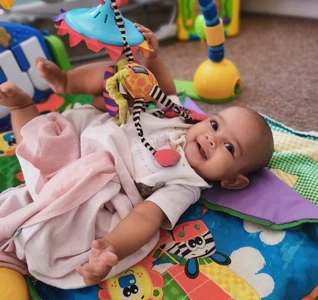 A baby happily lying on a colorful play mat surrounded by various toys, ready for fun and playtime. A baby happily lying on a colorful play mat surrounded by various toys, ready for fun and playtime.
