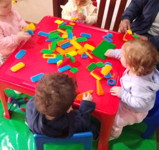 A fun scene of kids playing with blocks at a table, using their imagination to create different structures and designs. A fun scene of kids playing with blocks at a table, using their imagination to create different structures and designs.