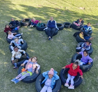 A group of kids sitting in a heart shape on a tire, smiling and enjoying their time together in a fun outdoor setting. A group of kids sitting in a heart shape on a tire, smiling and enjoying their time together in a fun outdoor setting.