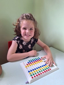 A young girl beams with joy as she plays with a bright and colorful puzzle, enjoying her fun activity. A young girl beams with joy as she plays with a bright and colorful puzzle, enjoying her fun activity.